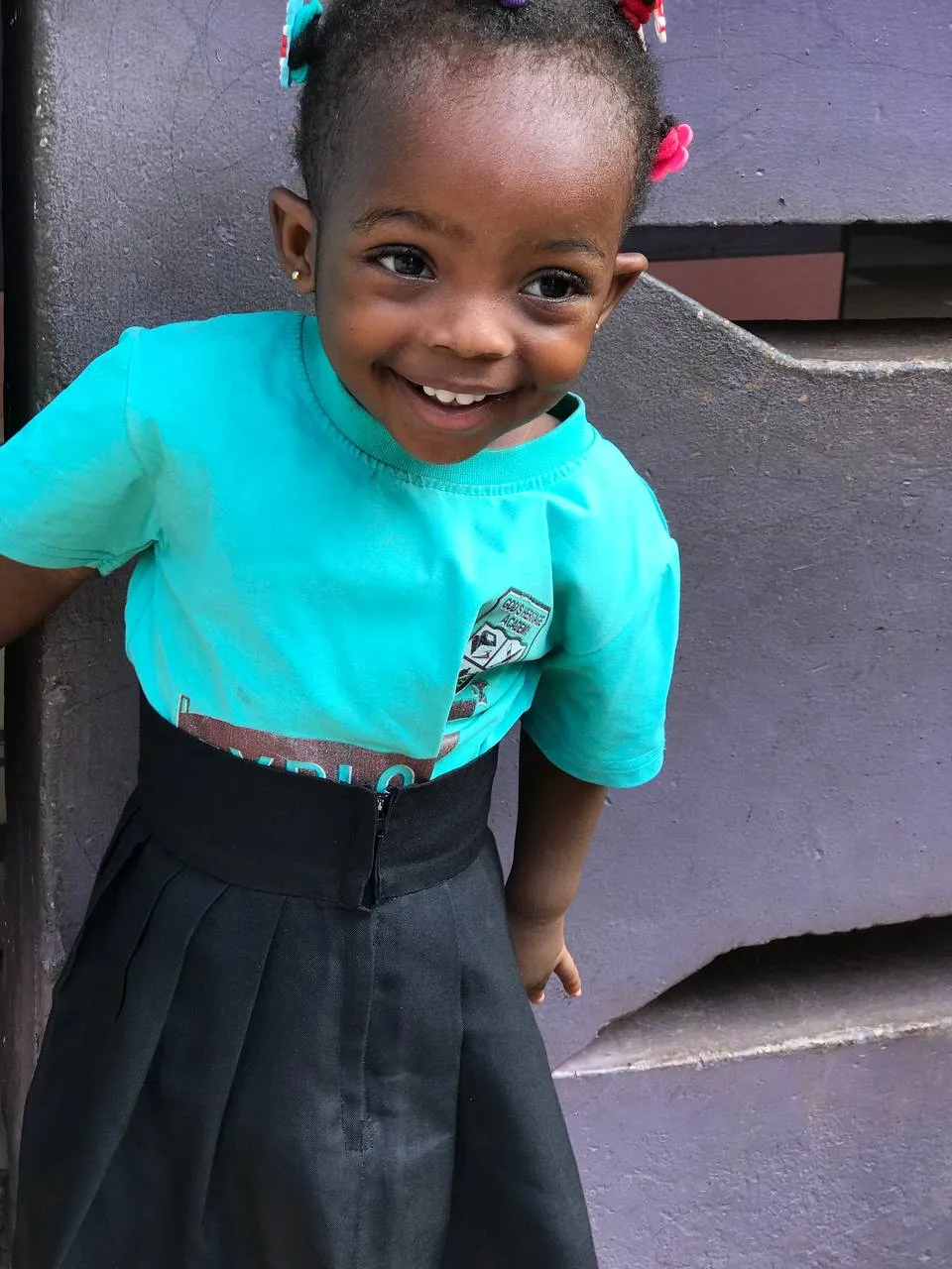 A young pupil in a teal shirt smiling at the camera
